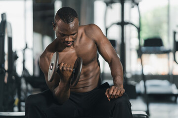 Fototapeta na wymiar African sport man strong muscle working out excercise in weights with dumbbell at fitness room at the gym. Body building sport man fitness concept.