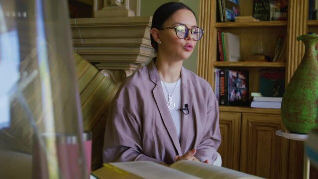 Beautiful writer recording a television show. Close-up of caucasian, brunette woman in glasses within charming interior. High quality 4k footage