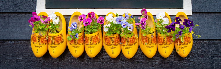 Old wooden Dutch shoes - klomps. A lot of colorful old clomps against the background of a wooden...