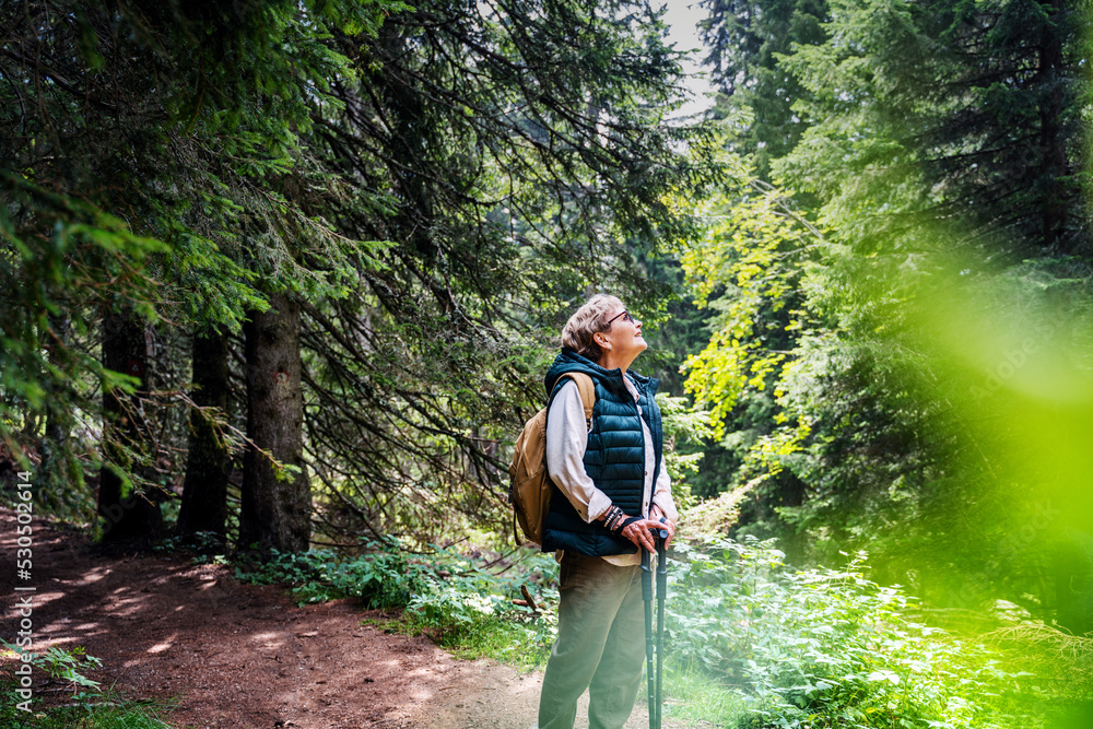 Wall mural active happy mature senior woman walking in beautiful autumn forest