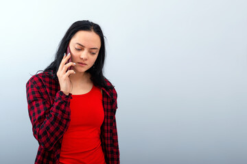 dark-haired emotional young woman in a red clothes talk on mobile phone, isolated, copy space