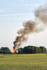 Fototapeta na wymiar Large fire on the horizon of an agricultural field with a huge pillar of smoke in de sky. Fire near Hallum Friesland in The Netherlands