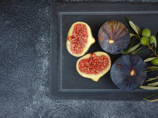 fresh ripe figs fruit and olive branch on dark table. mediterranean food concept