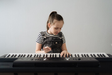 Child playing piano. Kids play music. Classical education for children. Art lesson. Little girl at white digital keyboard. Instrument for young student. Music class in school or at home. High quality