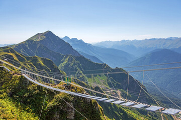 Suspension bridge with transparent floors is suspended in the mountains over an abyss. Away against the backdrop of the peak of the peak of the mountain.
