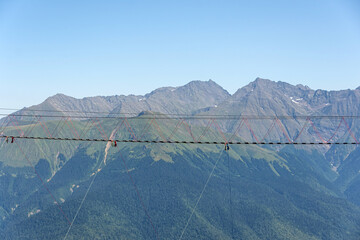 Suspension bridge in the mountains over the abyss. Away against the backdrop of the peaks of the...