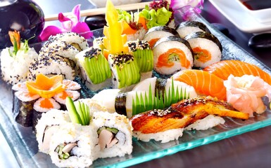 Big sushi set with maki, nigiri, dragon rolls. Sushi with salmon, tuna, raw fish, on a blue, glass plate.