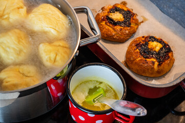 Fruit dumpling floating in boiling water, 2 colache and melted butter on hob.