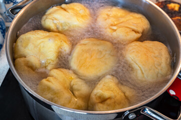 Sweet fruit dumplings floating in boiling water in pot.