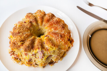 Salty tart on plate. Pasta with smoked meat and egg baked in cake tin.