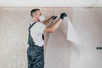 Male worker in coveralls applying fiberglass surface tissue on the wall