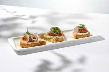Aesthetic composition with tomato bruschetta on white background with harsh shadows. Italian bruschetta with tomatoes and cheese on fine dining in summer. Elegant menu concept.
