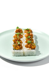 Sushi topped salmon tartare and micro greens Maki sushi with salmon in teriyaki sauce on ceramic plate. Salmon maki top tartare isolated on white background with hard shadow