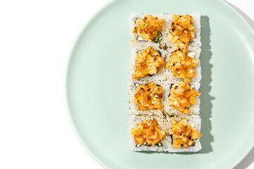 Sushi topped burnt shrimp tartare. Maki sushi with shrimp and spicy sauce on ceramic plate Baked maki roll topped shrimp tartare isolated on white background with hard shadow
