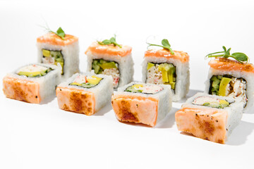 Maki sushi with baked salmon outside, avocado and crab meat inside topped micro greens Grilled salmon and avocado maki roll isolated on white background. Trendy sushi roll with burnt salmon fish