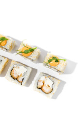 Maki sushi with sesame outside, tempura shrimp inside topped spicy sauce and microgreens. Spicy shrimp maki roll isolated on white background Trendy sushi roll with crispy prawn and hard shadows