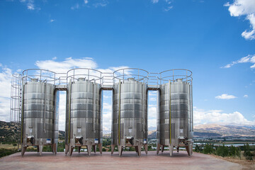 Modern steel clear wine tanks in the open air on blue sky and mountains background