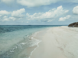 The deserted beach with white sand near the turquoise ocean. Maldives, tropical paradise.