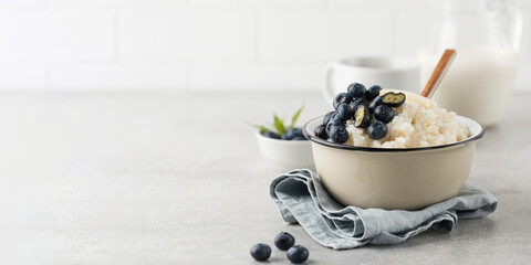 Rice pudding with blueberries in a bowl with a mug of coffee and a jug of milk. Healthy gluten free...