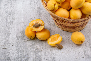 Ripe apricots in a wicker basket on a concrete background, close-up