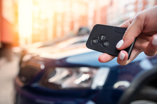 Man thumb presses button on remote control key removing alarm signal  bright car alarm light
