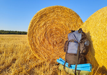 tourist backpack near large round haystacks in a golden field. Travel concept.