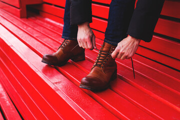 Men's hands tie the laces on their shoes. Stylish brown men's boots