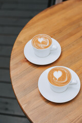 Cappuccino and flat white in white mugs on a wooden table. Coffee with a beautiful pattern for two....