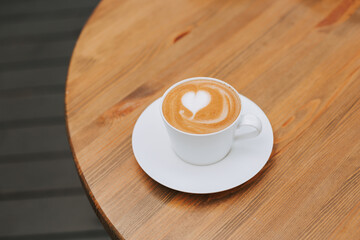 Double cappuccino with a beautiful foam and a heart in a white crook on the table. Beautiful coffee serving. Stylish aromatic coffee banner with space for text