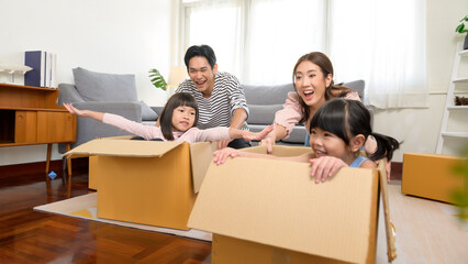Fototapeta na wymiar Asian family husband and wife and children with cardboard boxes having fun on moving day, Mortgage, loan, property and insurance concept.
