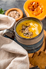  Cup of homemade pumpkin soup with seeds, sesame seeds and flax seeds close-up, warm autumn food vertical photo