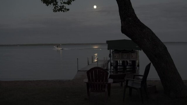 Lake in Bemidji, Minnesota, during the early evening with a full moon with boats going by in the background.
