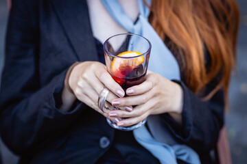 Female hands hold a transparent cup with mulled wine, close-up