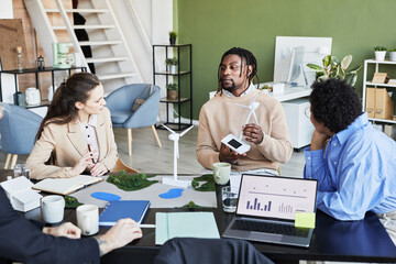 African businessman showing the new mockup of windmill to his colleagues at table at meeting