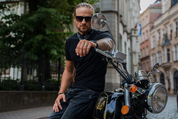 Fototapeta na wymiar Shot of man biker with his custom motorcycle at street in alley looking at camera.