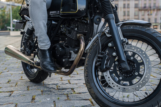 Shot of black modern motorbike with old fashioned pipe and man riding it.