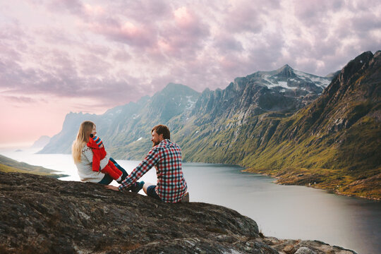 Family traveling in Norway man and woman with infant baby relaxing with mountains and fjord view summer vacations mother and father hiking with child healthy lifestyle eco tourism