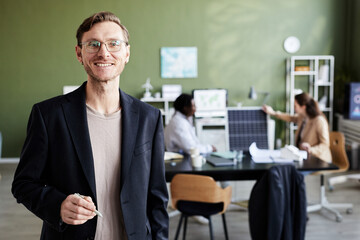Portrait of young professional engineer smiling at camera while standing at office