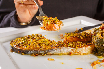 Salmone cotto al forno in crosta di granella di pistacchi con contorno di scarole saltate in padella servito in un ristorante 