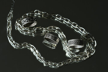 Metal jewelry rings and bracelets on mirror background, fashion and accessories