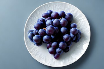 Top view of a plate with bright purple grapes on a blue background