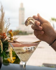 Vertical shot of a person scooping a tiramisu dessert in a martini glass