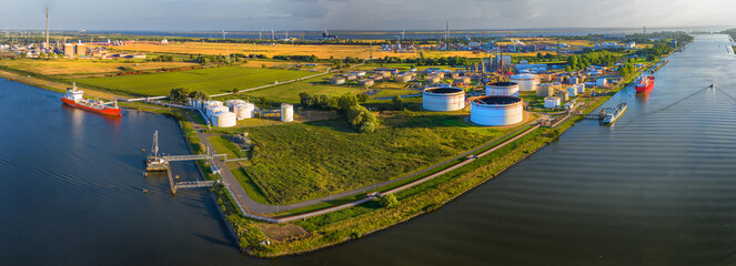 Drone view of industrial complex with gas, oil and hydrogen storage. With wind power in the background. - obrazy, fototapety, plakaty