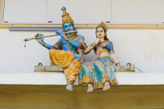 Divine couple - Radha and Krishna are sitting on the wall of the temple. Religious sculpture of the Hindus. Krishna plays the flute for Radharani. Dharmasthala, Karnataka.