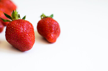 Three strawberries with strawberry leaf on white background.