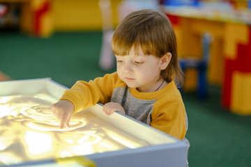 Creative child development. Baby draws sand on glass. Early development of children. Development of...