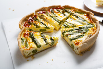 Close up of sliced open faced savory asparagus pie food on light surface