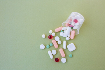 Many different pills in plastic cup on green background. Copy space. Concept of pharmaceuticals