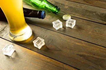 Foto op Canvas Image of beer bottles, ice cubes and pint glass of beer on wooden table, with copy space © vectorfusionart