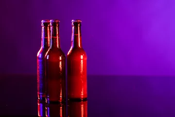 Keuken spatwand met foto Image of three brown beer bottles with crown caps, with copy space on purple background © vectorfusionart